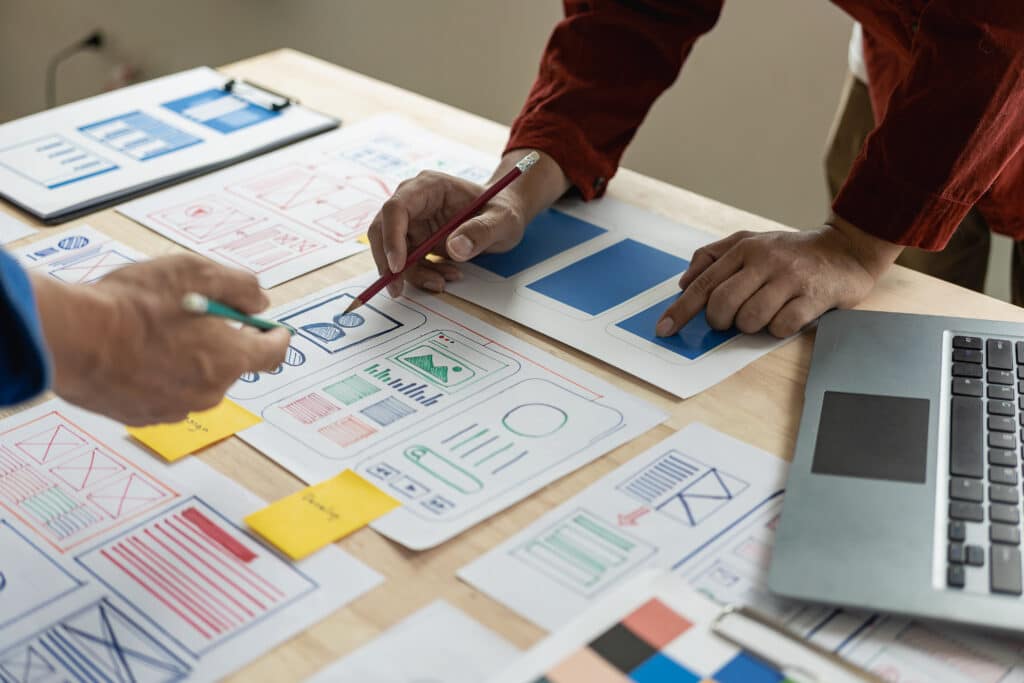 Heartbeep Marketing NH SEO Agency in Boston, A team of web designers are working together to develop a mobile responsive website with UI/UX front end design concepts. A team of UxUi developers are working together at a wooden workbench.